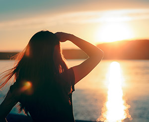 breast care information, woman thoughtfully looking at sunrise on the water